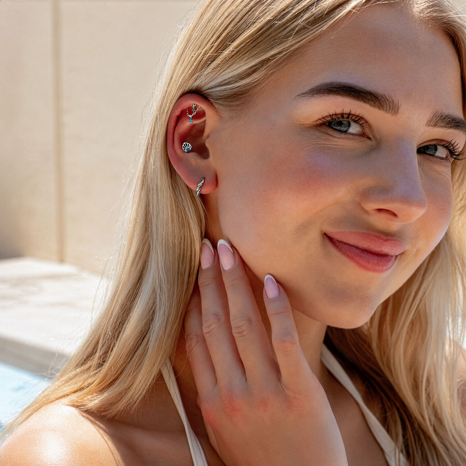 Doppio piercing elica turchese all'orecchio Primo piano di una donna con doppio piercing elica turchese in titanio all'orecchio, alla luce del sole
