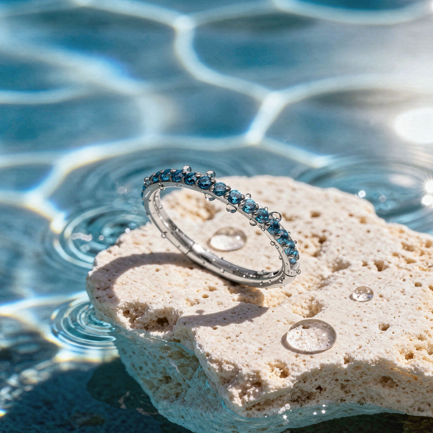 Anello di cristallo turchese su pietra Anello di cristallo turchese su una pietra chiara al bordo di una piscina con riflessi di luce solare