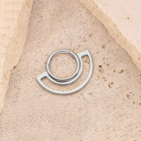 Clicker a Doppio Anello in Argento su Pietra Clicker ad anello in argento su sfondo di pietra beige, design circolare