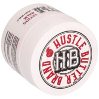 Barattolo bianco con marchio Hustle Butter e scritta rossa, sdraiato su un lato