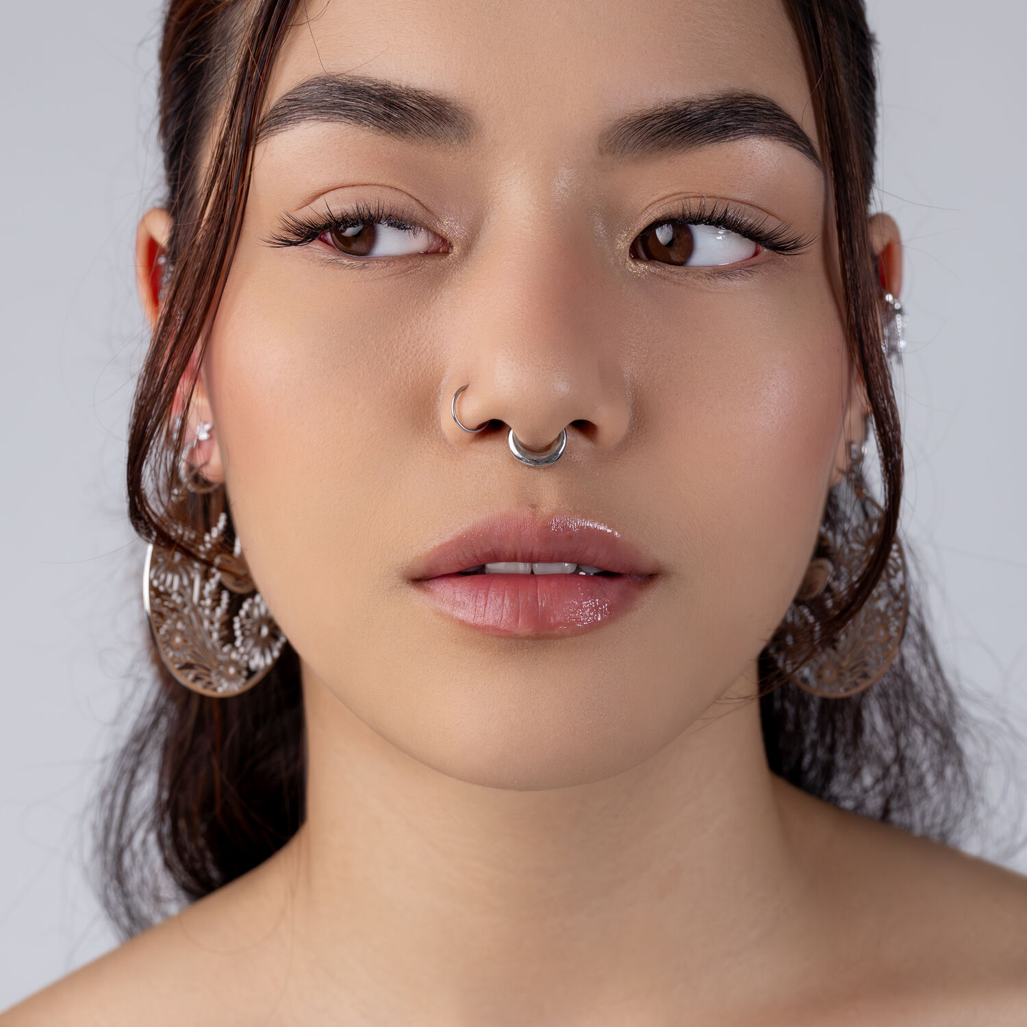 Chunky Septum Clicker in argento Primo piano di un viso con septum clicker in argento e grandi orecchini