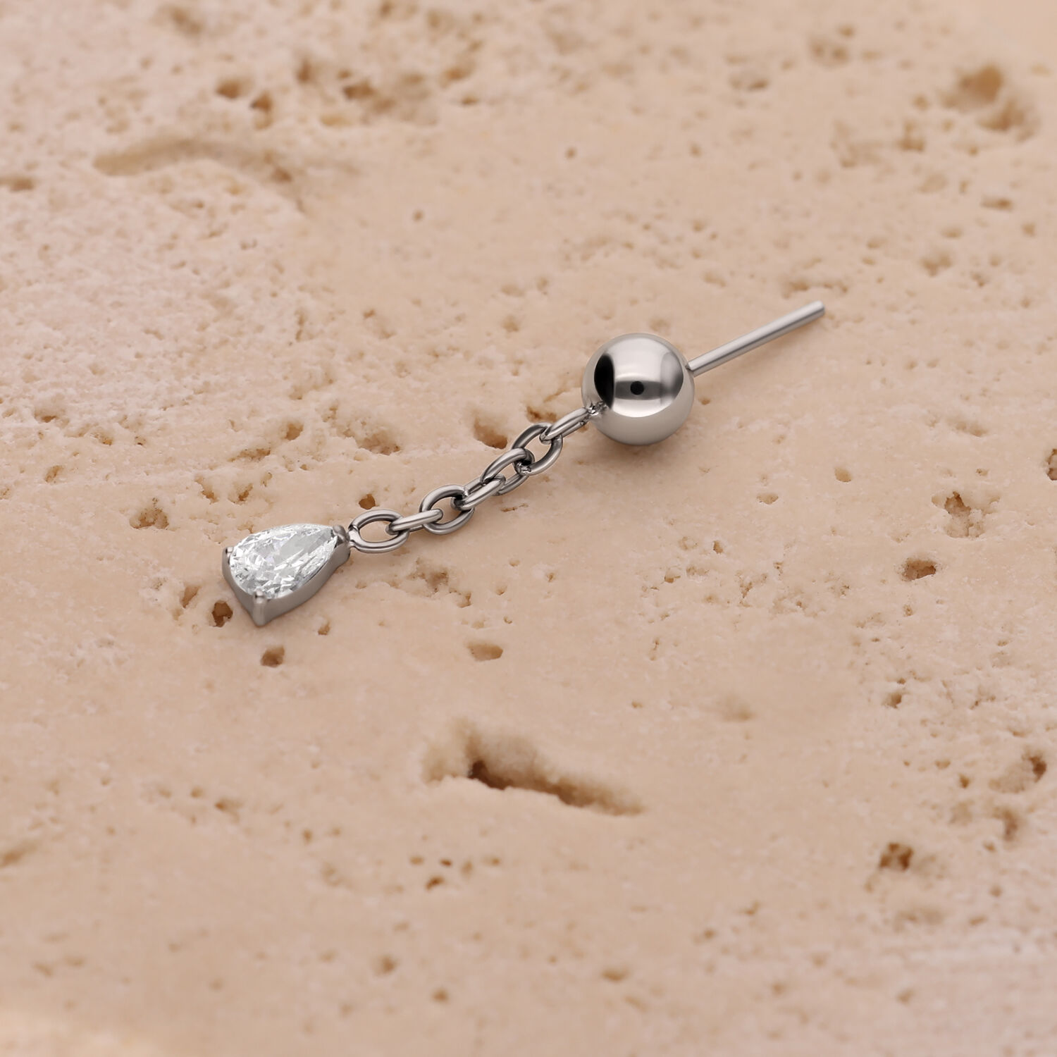 Ciondolo per piercing all'orecchio in argento con catena Ciondolo in argento con catena e cristallo ovale su sfondo beige