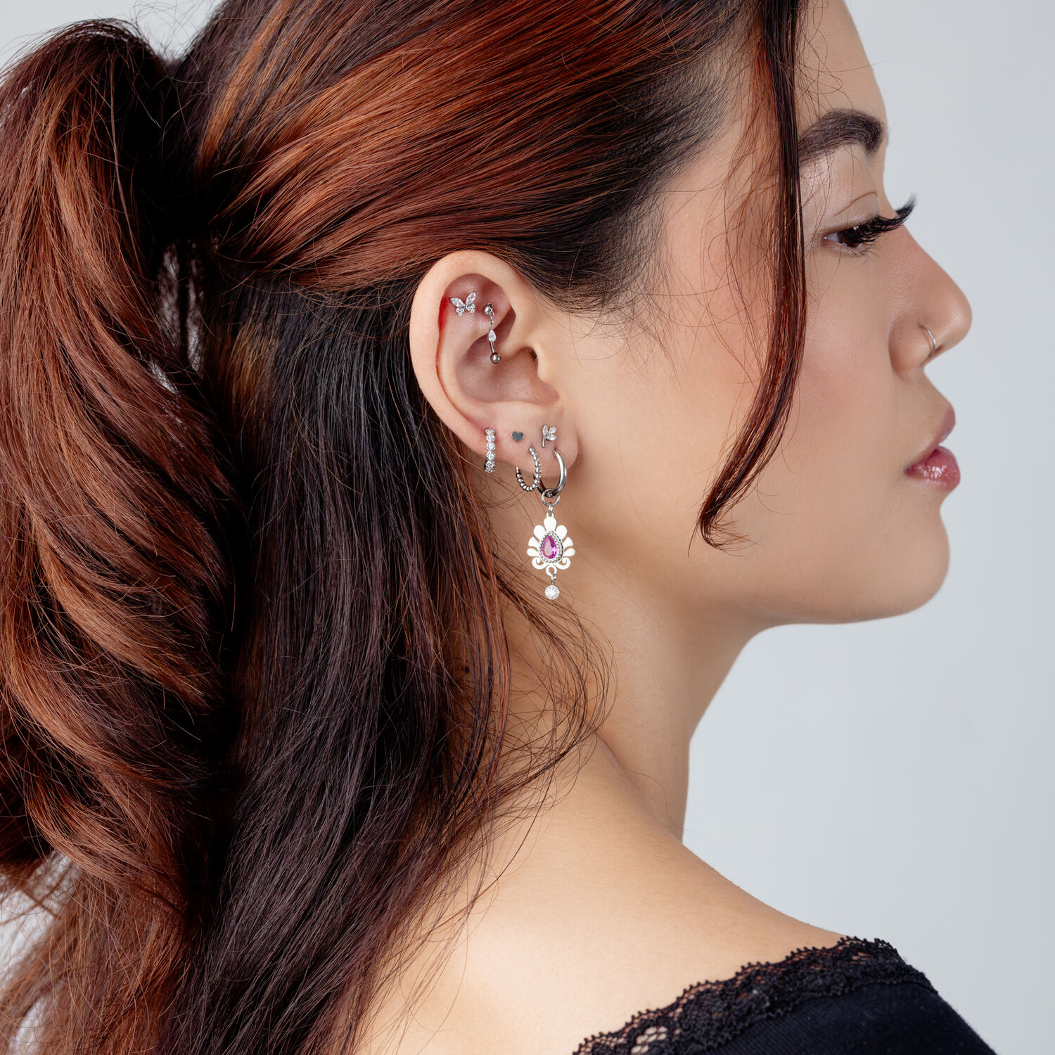 Accessorio per piercing all'orecchio in argento con cristallo Donna con diversi orecchini in argento e un accessorio con cristallo nell'orecchio, vista laterale