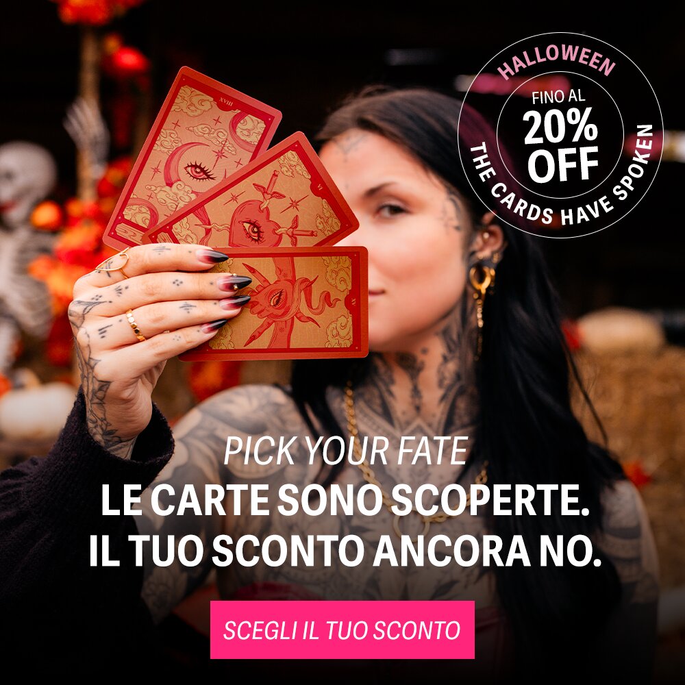 Donna con tatuaggi tiene carte rosse di tarocchi, sfondo sfocato